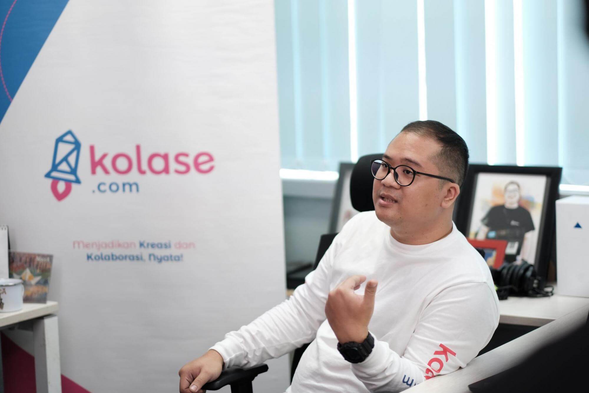 Founder Kolase.com duduk di depan banner bertuliskan Kolase.com